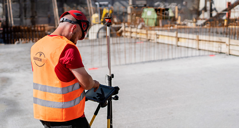 Rakennustyöntekijä käyttää rakennustyömaalla Leica iCON iCR80 -laitetta ja Leica CC80 -maastotallenninta.